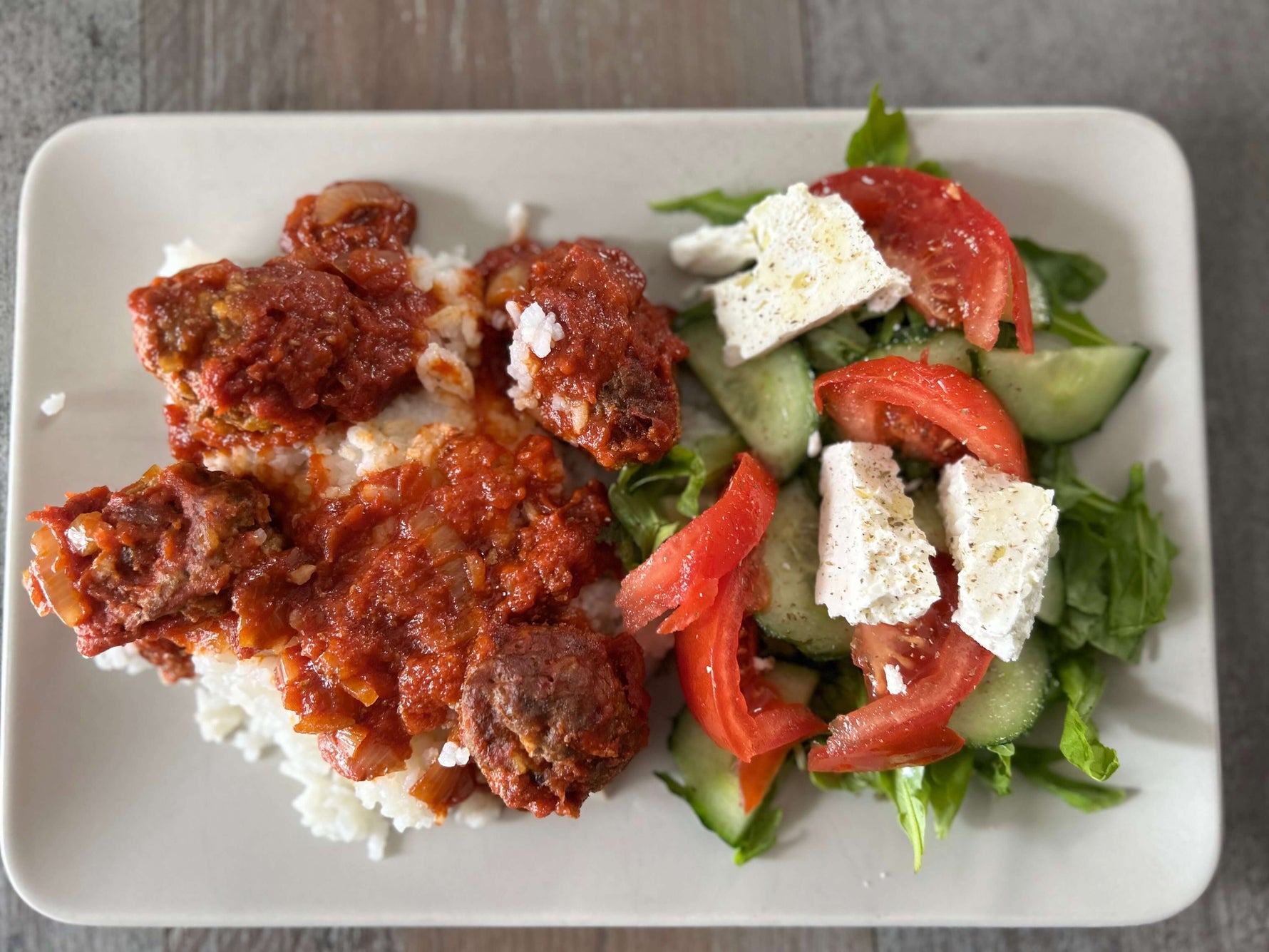 Pfefferminzöl-Soutsoukakia auf einem Teller mit griechischem Salat. Ein traditionelles Sonntagsgericht.
