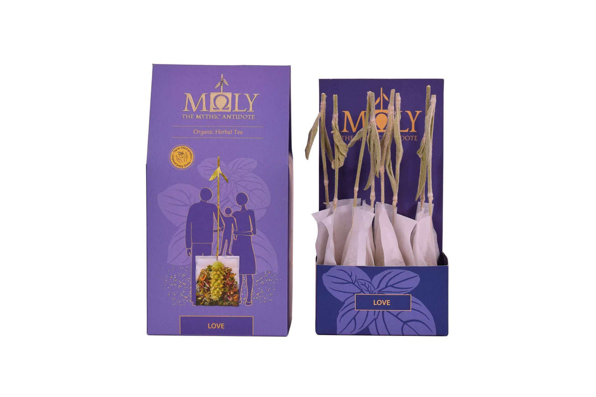 Eine lila Verpackung mit MOLY Love. Zentral ist Bild aufgedruckt, welches einen Teebeutel mit Inhalt zeigt aus dem der Stengel der Sideritis scardia (griechischer Bergtee) herausragt. Daneben ist der Inhalt der Verpackung zu sehen, der aus zehn einzelnen Teebeuteln mit jeweils einem Sideritis-Stengel besteht.